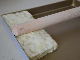 花生牛轧糖,用擀面杖将表面擀平整。