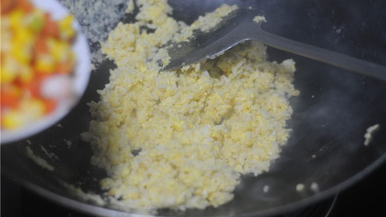虾仁炒饭,直到蛋液凝固，均匀地包裹米饭，倒入汆烫好的蔬菜粒