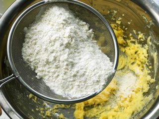 贝壳小饼干,将低筋面粉筛入黄油糊，用橡皮刮刀翻拌均匀；