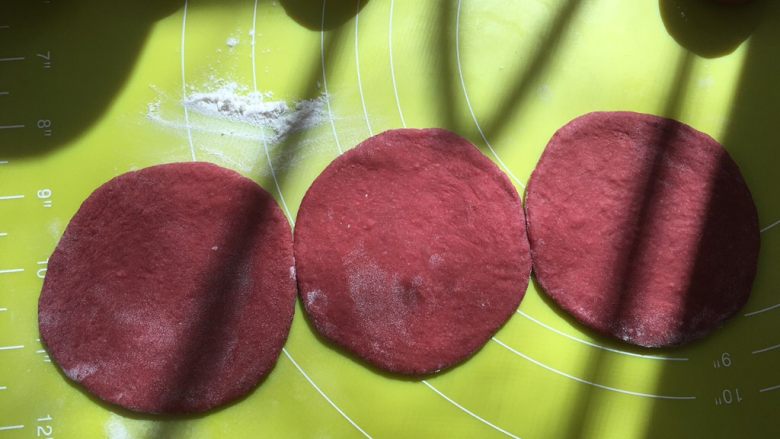 双色玫瑰花面包,撒一点干粉，将松弛好的红色面团擀成圆片，大小要均匀