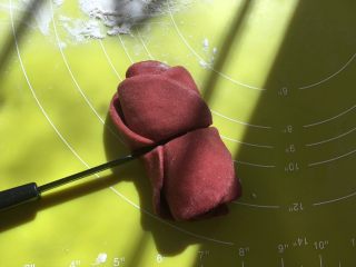 双色玫瑰花面包,卷好后，用刀沿着筷子压出的痕迹，从中间切开，玫瑰花就做好啦，底下撒点干粉，放一旁备用