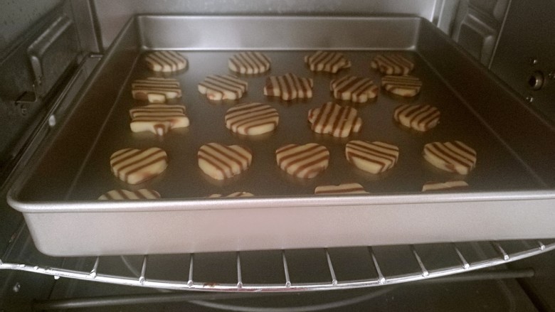 双色条纹花生饼干,将切好的饼干均匀的摆在烤盘上，放入预热好上下火175度的烤盘，烘烤12分钟左右即可。