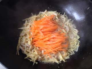 扬州春卷,放入胡萝卜丝，并调入1g盐和鸡精翻炒片刻