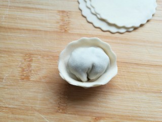 荠菜元宝水饺,将半圆的两端向中间圆心处弯拢并捏住。