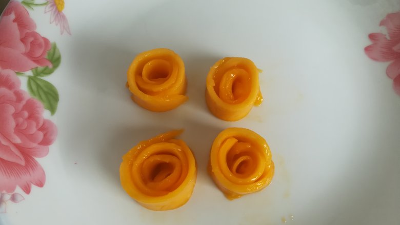 四季慕斯四重奏,取几片芒果片卷成玫瑰花，放入冰箱冷藏