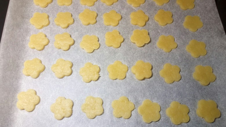 辅食计划~黄油花朵小饼干,将所有的饼干整齐地摆放到铺有油纸的烤盘里。