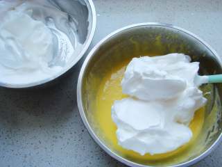10寸戚风蛋糕,把打好的蛋白分一半倒入蛋黄糊糊里。呈“J”字形翻拌，不可划圈避免消泡。