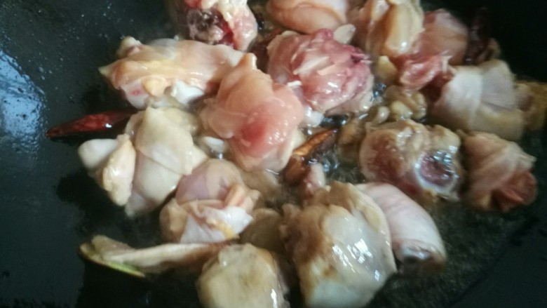 家常黄焖鸡,糖色炒好后放入腌制好的鸡块，煸炒至鸡肉表面变色。