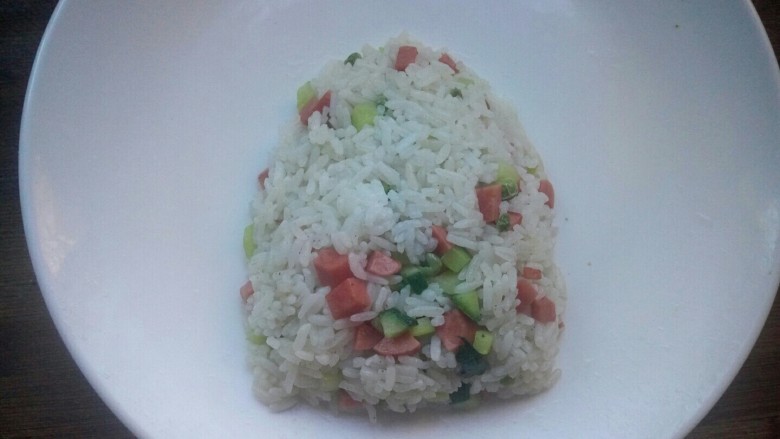 创意菠萝饭,翻炒片刻后盛入盘中，将米饭整形为上小下大的形状。