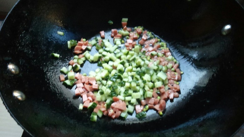 创意菠萝饭,先将火腿丁和黄瓜丁略翻炒两下。