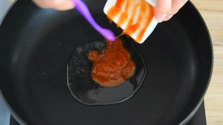 如果你爱吃甜，那么绝对不能错过这道菜,锅里倒入一勺油，放番茄酱滑散。