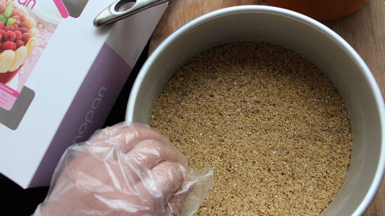 8寸芒果慕斯,将混合好的燕麦底倒入模具，用手和刮刀压平整，然后放入冰箱冷藏。