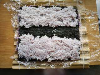 翻转花朵寿司,在海苔上铺一层浅色米饭或白色米饭。 中间留一段不铺。