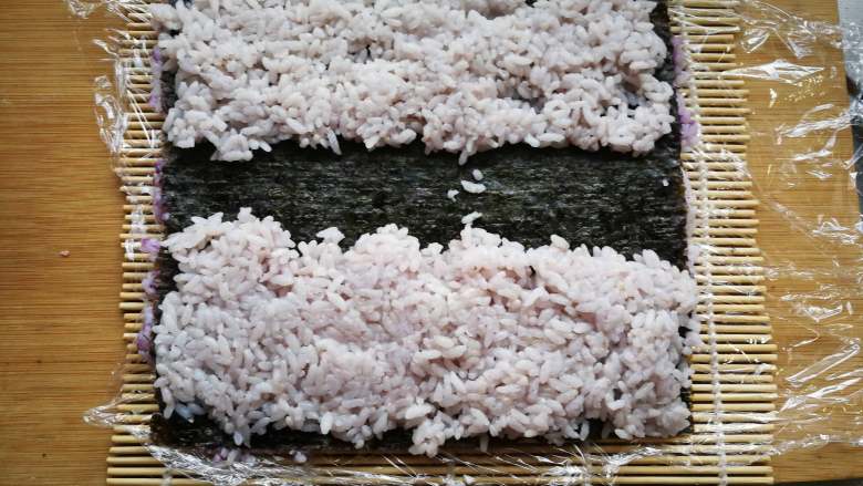 翻转花朵寿司,在海苔上铺一层浅色米饭或白色米饭。 中间留一段不铺。