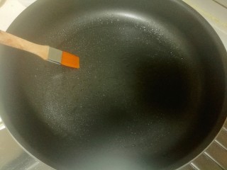 油酥葱花饼,将锅预热，在锅中倒入一些油，并用刷子涂抹开来。