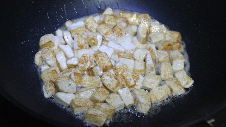 孜然小葱煎豆腐,待豆腐煎至金黄色时，掂几次锅让豆腐煎的更均匀些。