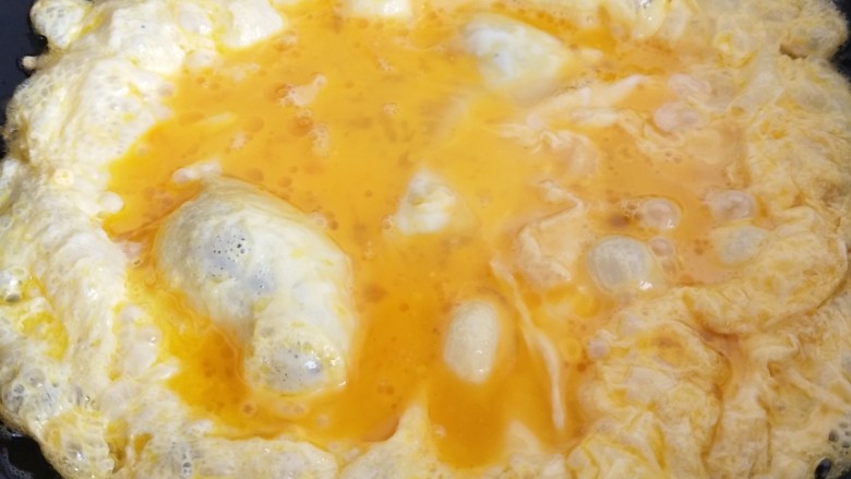 青蒜炒鸡蛋,转动锅让鸡蛋摊平并慢慢熟