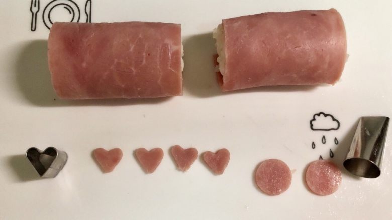 小萌猪火腿饭团,在另一片火腿片上，用心形模具切下4个爱心形做小猪的耳朵。用裱花嘴圆形的一端切下两个圆形做小猪的鼻子。