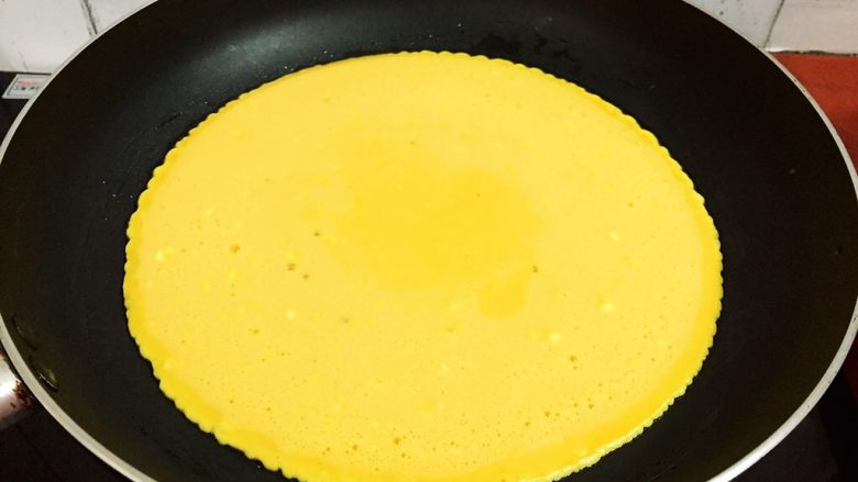 鸡蛋豆沙卷,倒入鸡蛋液，摇晃锅子使蛋液均匀的摊开