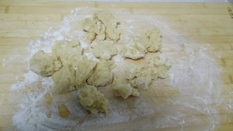 炸糖糕,案板上撒入少许干粉——防粘，把烫好的面揪成小块晾凉。