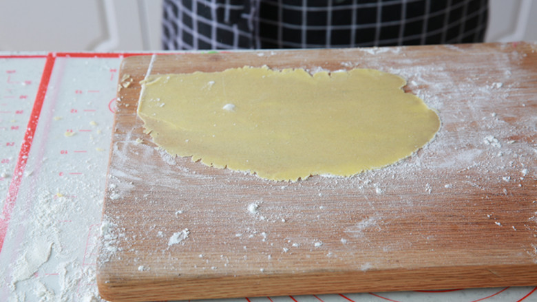 菠萝奶酥吐司,取出冷藏的菠萝皮，案板上撒薄粉，把菠萝皮擀成薄片状。