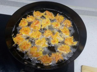 胡萝卜丸子,锅中放入适量油，五层热，用勺子挖一勺，放入手上用勺子团圆，再放入锅中。