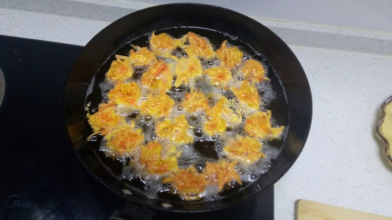 胡萝卜丸子,锅中放入适量油，五层热，用勺子挖一勺，放入手上用勺子团圆，再放入锅中。