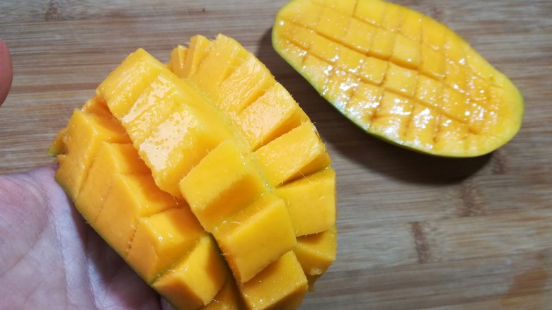 芒果酸奶杯,手在芒果皮位置往上一顶，芒果就会成图中的状态。这时就可以很方便的切下芒果的小块。