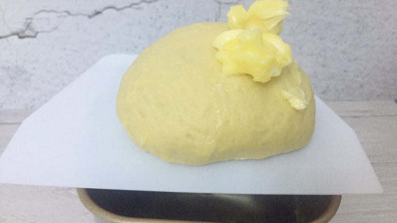 辣肉松面包卷,扩展阶段即面团可拉出厚膜时，加入黄油，继续和面揉至完全阶段。此时面团可以拉出薄且不易破的膜。