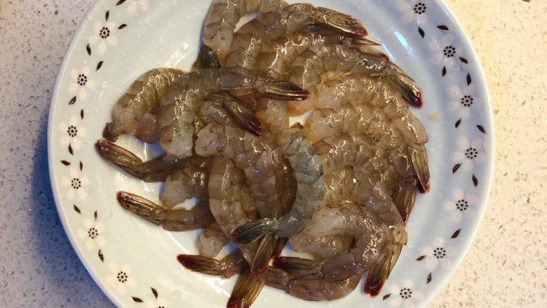 虾扯蛋,把冰箱里取出的冻虾冲软后，剥壳去虾线，只留下尾部的壳。