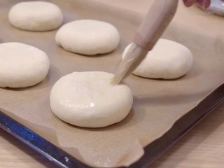 日式红豆包,滚圆，包封口朝下，压一下，烤盘里铺一张烘焙纸，豆包码放在烤盘里，用刷子薄薄的刷一层水