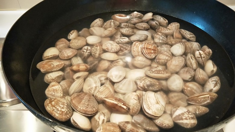 麻辣爆炒花蛤,锅中放适量水烧开，放入花蛤煮开后捞出来备用。