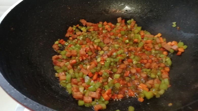 黄油版&黄金火腿蛋炒饭,把芹菜丁，胡萝卜丁和火腿丁放进锅里翻炒。