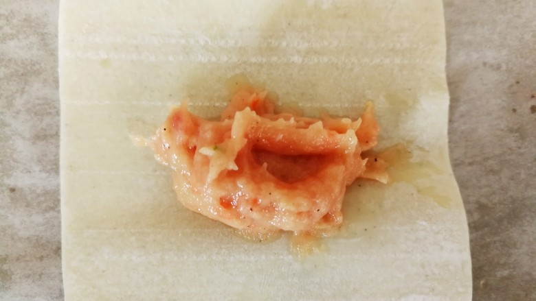 胡萝卜巴沙鱼牛肉小馄饨,取一张馄饨皮，挖适量的馅料放在中间