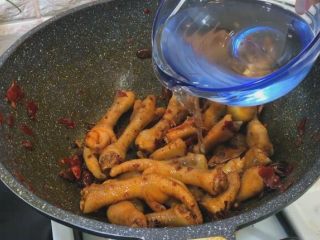 鸡爪烧豌豆,鸡爪翻炒均匀 加入清水没过鸡爪