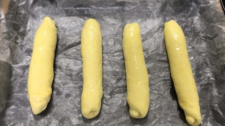 桃李毛毛虫奶油面包,然后搓成均匀的长条，长度基本一致即可，放入烤盘，放在温热的地方二次发酵至原来两倍大。刷鸡蛋液。