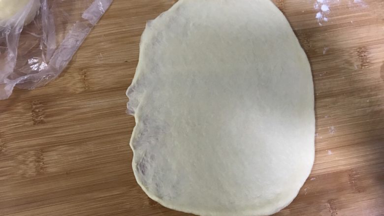 桃李毛毛虫奶油面包,拿起一个擀成椭圆形，左边用手按薄。