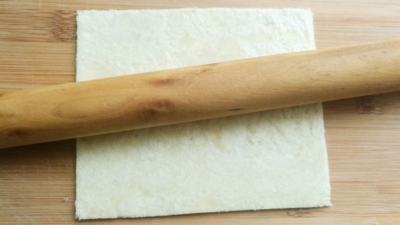 辅食计划十牛油果香蕉卷,用擀面杖将面包片擀薄。