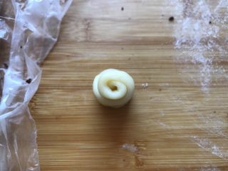红豆蛋黄酥,醒发好的小面卷拿出来竖直朝上放置，按扁，向上向下各擀一下，再从上往下卷起。