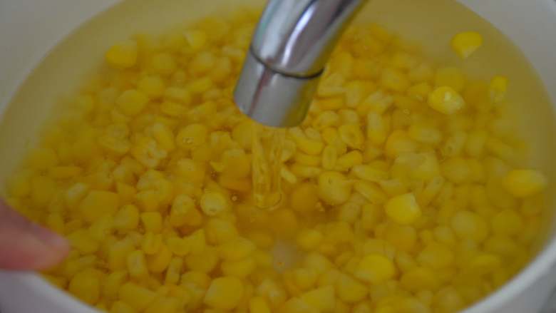 黄金玉米烙,将玉米粒放在水龙头下冲洗两遍，稍微放凉，去除多余的水分。
（注意：玉米粒表面不能太干，状态是湿湿的，否则裹不上淀粉）
