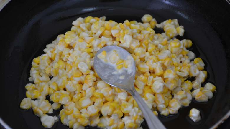 黄金玉米烙,锅中放入少许油，转动锅子，使油均匀地涂在锅底，然后放入裹好淀粉的玉米粒。