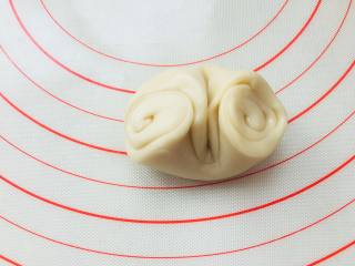传统蛋黄酥,去一个面团，螺旋开口朝两头，在中心位置按压一下，将两头螺旋位置往中间收，边收边按扁。擀成圆形。