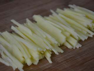 凉拌土豆丝,左手压住土豆片，右手将土豆片切成丝。