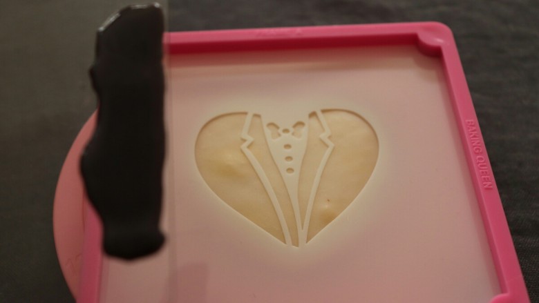 糖霜饼干之婚礼系列,饼干冷却后，给饼干铺个面，颜色可根据自己喜好。然后烘干或者自然晾干，放上印花模，刮板上涂抹黑色的糖霜。