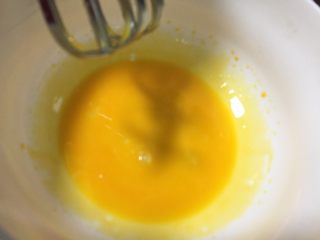 芒果慕斯蛋糕,蛋黄液用打蛋器打发，奶锅加入白砂糖和清水煮至沸腾融化关火，糖水趁热倒入蛋黄液