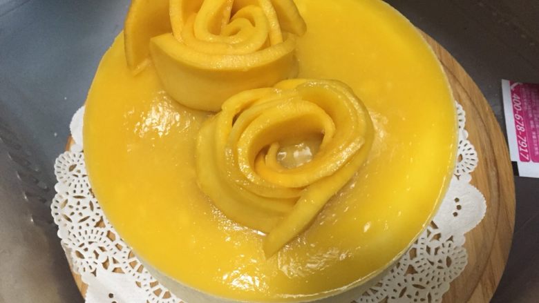 芒果慕斯蛋糕,最后将芒果切片摆成玫瑰花状于慕斯蛋糕表面，放入冰箱冷藏半小时即可