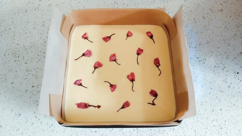 樱花烫面蛋糕,倒入垫了油布的8寸方模，放上事先处理好的樱花 。