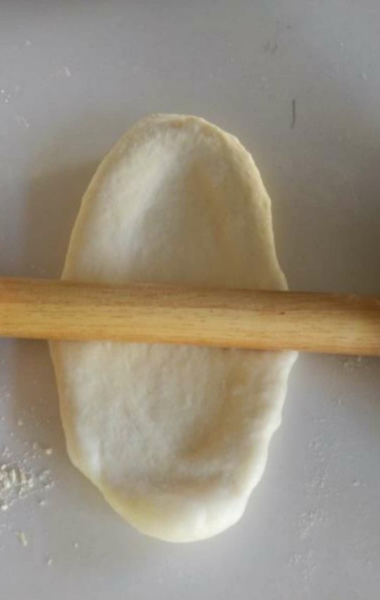 黄金椰蓉吐司,将面团用擀面杖擀成长方形类似牛舌状。