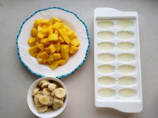 香蕉芒果冰沙,芒果去皮后切成块，香蕉切片后放入冰箱冷冻一晚，纯牛奶放入冰格中冷冻成块。