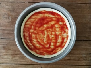 薄底香肠披萨,烘烤5分钟后的披萨底取出，用勺子涂抹一层番茄酱